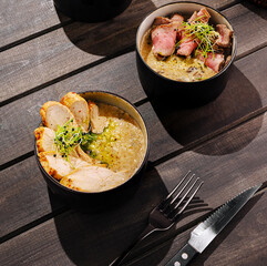 Gourmet chicken and beef soup bowls served on a wooden table