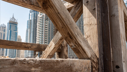 Construction site with wooden scaffolding against city skyline during daytime in a modern urban environment