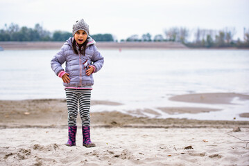 Surprised girl wearing winter clothes standing on river bank