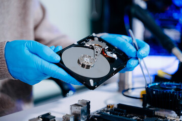  Hard disk drive on the technician's desk and a computer motherboard as a component. the concept of...