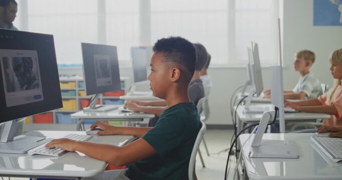 Elementary School Children Using Computers, Creating Illustrations in AI Image Generator. African American Teacher Teaching Young Boys and Girls During Digital Art Lesson. STEM Education. Dolly Shot.