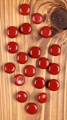 Round red candies on a wooden surface