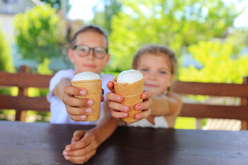 two children savoring ice cream cones while enjoying a sunny day outdoors