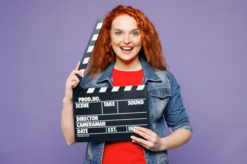 Young smiling happy ginger woman wears red t-shirt denim shirt hold in hand classic black film...