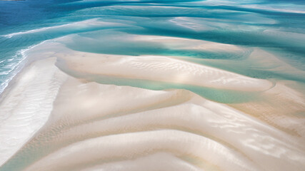 Aerial view of shifting sands create a mesmerizing dance of light and shadow where turquoise waters meet the bleached shore, Moreton Island, Queensland, Australia.