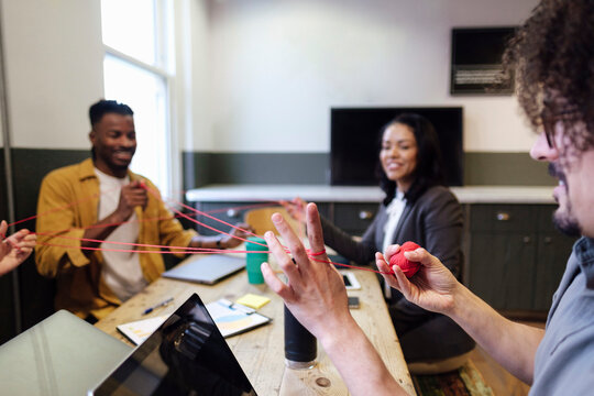 Businessman playing cat's cradle with colleagues at office