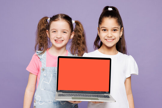 Little smart two friends kids children IT girls 9-10 years old wear casual clothes together hold use work on blank screen area laptop pc computer isolated on plain purple background Lifestyle concept