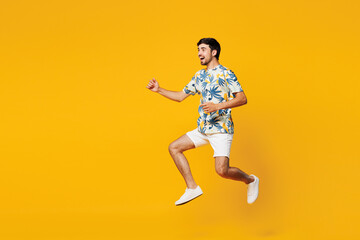 Obraz premium Full body side view young smiling happy Caucasian man he wear blue beach t-shirt casual clothes jump high run fast isolated on plain yellow orange color background studio portrait. Lifestyle concept.