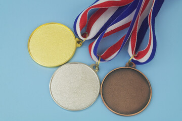Gold, silver and bronze medals with ribbons on blue background
