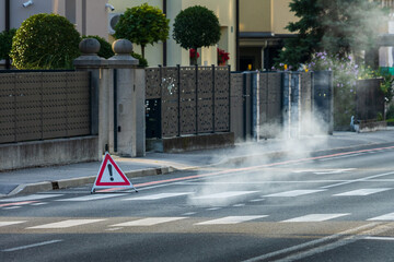 safety alert street warning sign with rising steam near crosswalk