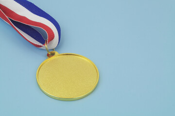 Gold medal with ribbon on blue background. Copy space for text.