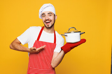 Young happy housewife housekeeper chef cook baker man wear red apron toque hat oven mitt hold in...