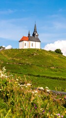 Small church atop grassy hill, vibrant colors, clear sky