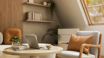 Laptop with book and a glass of coffee on wooden round table under roof window in sunlit living room