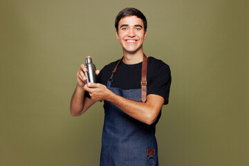 Young smiling man barista bartender barman employee wear jeans apron t-shirt work in night club...