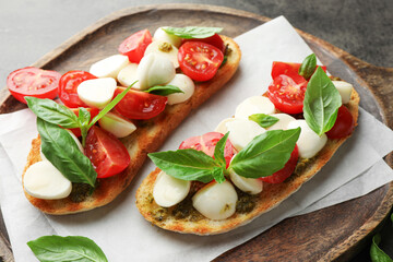 Delicious sandwiches with mozzarella cheese, tomatoes and basil on grey textured table, closeup