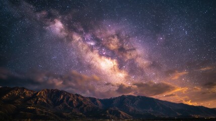 Naklejka premium Panorama of the Milky Way, with its ethereal glow illuminating the night sky above a majestic mountain range.