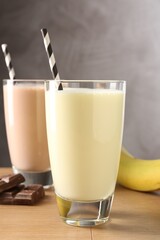 Tasty milkshakes in glasses and ingredients on wooden table, closeup