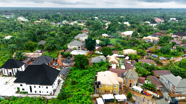 Aerial view of houses nestled among verdant trees, the landscape a tapestry of green and brown, creating a serene yet vibrant community,  Okwele Community, Imo State, Nigeria.