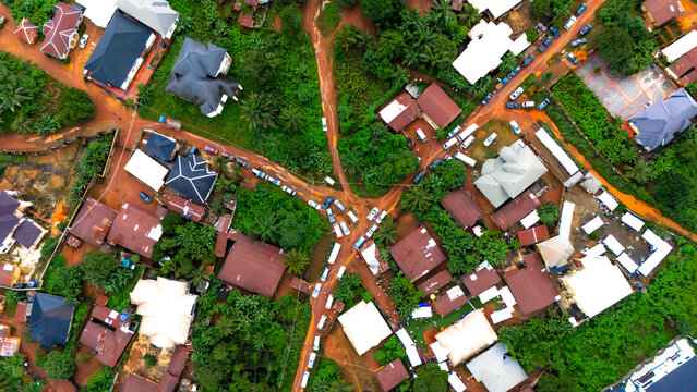 Aerial view of rustic rooftops nestled amidst vibrant green foliage, crisscrossed by earth-toned pathways, creating a striking contrast,  Okwele Community, Imo State, Nigeria.