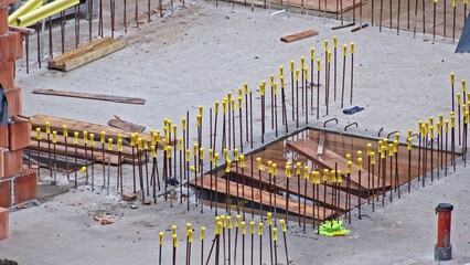 Construction Site with Metal Reinforcement Rebar Rods Secured with Yellow Safety Caps to Prevent...