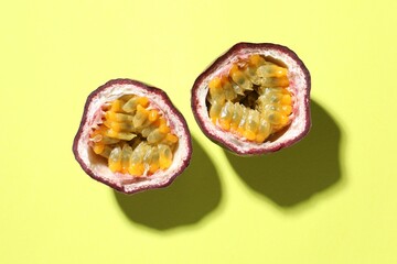 Halves of fresh passion fruit on pale green background, flat lay