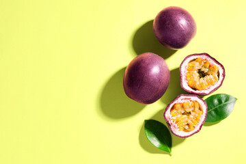 Fresh passion fruits and leaves on pale green background, flat lay. Space for text