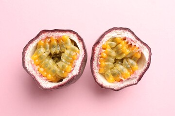 Halves of fresh passion fruit on pink background, flat lay
