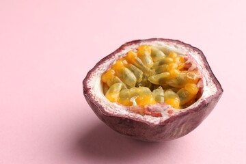 Half of fresh passion fruit on pink background, closeup. Space for text