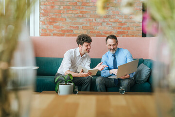 Businesspeople discussing work on laptop during meeting indoors