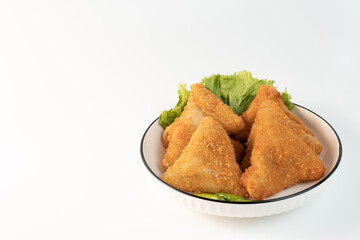 Risol Mayo segitiga or Triangle Risol mayonnaise served in a white bowl with fresh lettuce and green chili on white background. Showcasing a savory Indonesian snack with breadcrumb coating. copy space