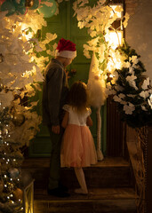 Brother and sister in the middle of New Year's decorations. View from behind.