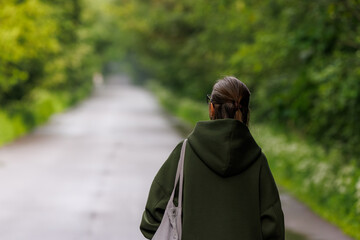 Woman walking on a serene path surrounded by lush greenery in a quiet moment of reflection