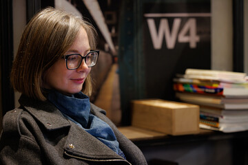 Woman with glasses focuses on laptop while relaxing in modern cafe