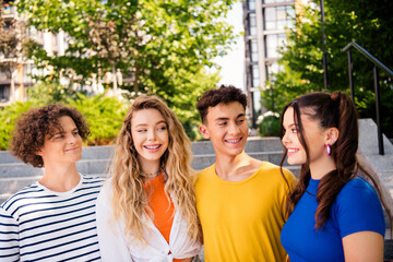 Group of cheerful young friends enjoying a sunny day outdoors, showcasing their bond and happiness on urban stairs