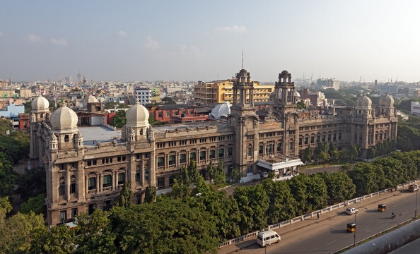Aerial view of the grand, ornate architecture of the Madras High Court, its domes gleaming against the urban sprawl, framed by lush trees and bustling streets, Chennai, Tamil Nadu, India.