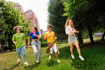 Obraz premium Group of diverse friends enjoying a sunny day outdoors in a park setting with nature and urban background