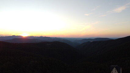 Obraz premium Sunset Over Mountain Range and Forest – Aerial View Landscape 