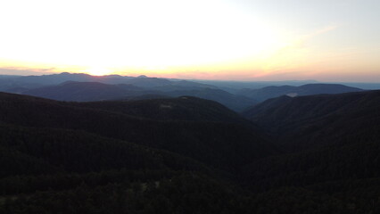 Fototapeta premium Sunset Over Mountain Range and Forest – Aerial View Landscape 