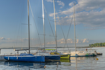 Sailboats docked at quiet marina under clear blue sky. Yachts moored quietly in the harbor, poised...