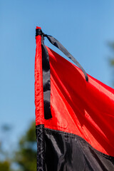 Red and black Ukrainian flag with black mourning ribbon, symbol of struggle and remembrance.