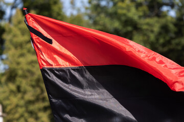 Red and black Ukrainian flag with black mourning ribbon, symbol of struggle and remembrance.