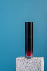 Mockup of black blank thin tube - mascara, lip gloss, gel, eyeliner, oil, etc. Cosmetic package with stylish props on blue background.