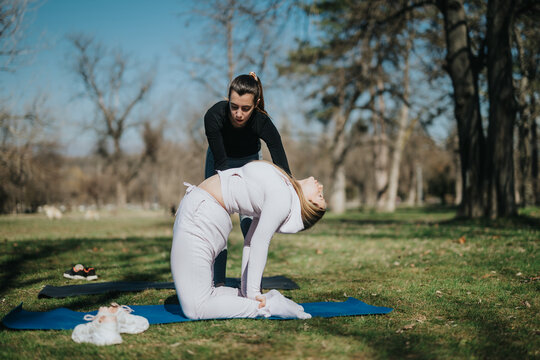 A tranquil scene featuring a yoga instructor assisting a student with a deep back bend pose outdoors in a lush park environment under clear skies.