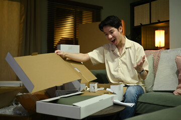 An excited customer is enjoying the surprise of a new delivery, unboxing it in a relaxed home at...