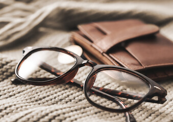 Stylish Eyeglasses and a Chic Wallet on Soft, Cozy Textiles for a Fashionable Look