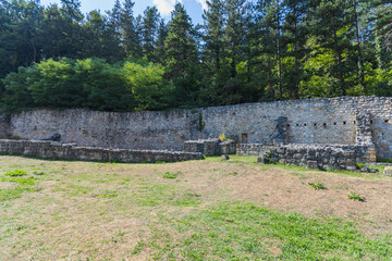 Historic stone fortification ruins at Studenica Monastery complex, surrounded by lush forest,...