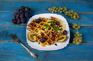 fresh waffles with syrup and ripe fruit for breakfast