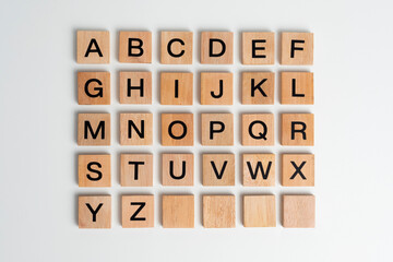Alphabet letters on wooden scrabble pieces, isolated on white.