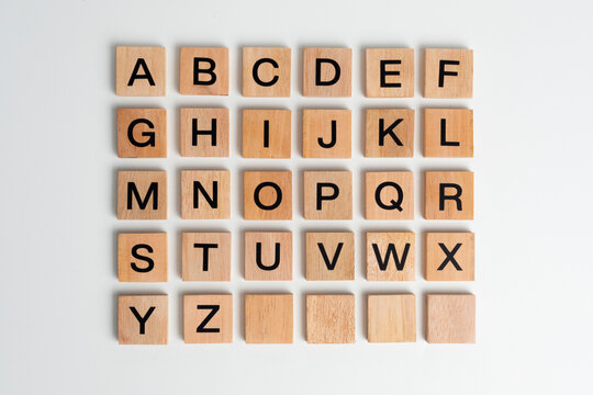 Alphabet letters on wooden scrabble pieces, isolated on white.